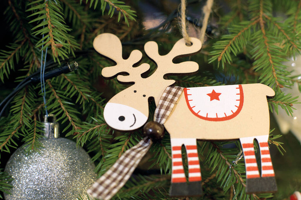 Wooden reindeer toy on the Christmas tree next to other toys. - Foto, Imagen