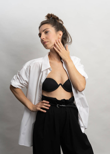 Model, brunette poserend op een witte achtergrond in de studio. Ze draagt een wit shirt, een zwart kapsel. Foto tot aan de taille - Foto, afbeelding