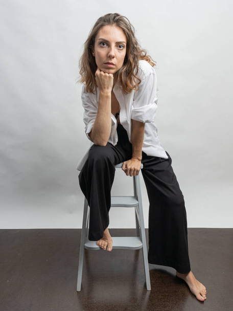 Model, brünett mit Strohhut posiert auf weißem Hintergrund im Studio. Sie trägt ein weißes Hemd, eine schwarze Frisur. - Foto, Bild