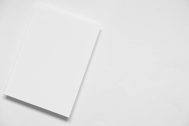 Draufsicht auf blank saubere weiße vertikale Mock-up-Broschüre mit sanftem Schatten auf blankem weißem Papierhintergrund. - Foto, Bild