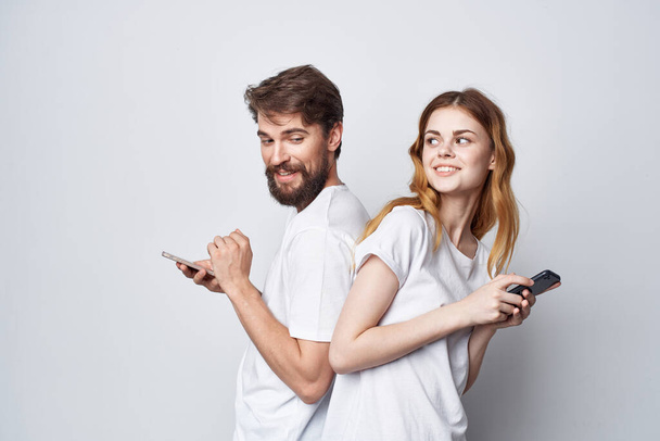 man and woman in white T-shirts with phones in their hands isolated background - Фото, изображение