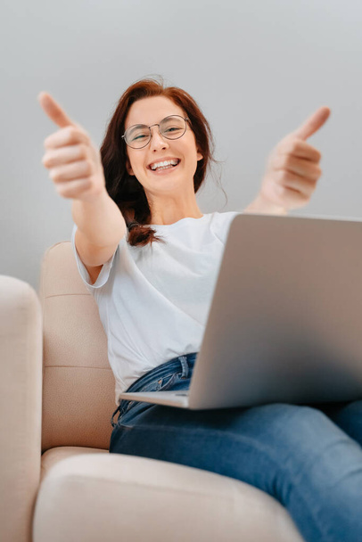 Happy woman showing a thumbs-up gesture recommending a job. - Foto, Bild