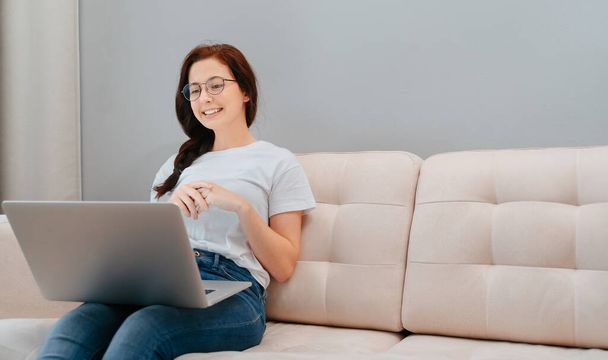 A young satisfied woman listens to an interlocutor on a laptop online. - Fotó, kép