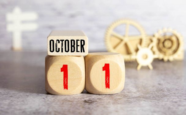 Weißer Blockkalender präsentiert Datum 11 und Monat Oktober auf Holzhintergrund. - Foto, Bild
