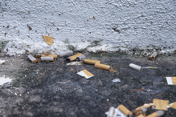 Pozostałości niedopałków papierosów przy rogu brudnego odpływu. - Zdjęcie, obraz