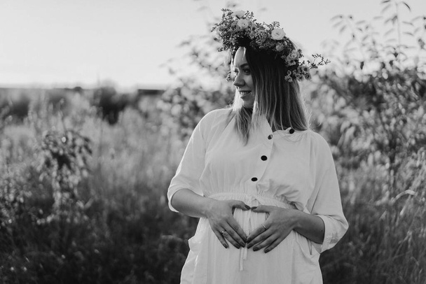 Hamile bir kadının portresi. Beyaz elbiseli güzel hamile bir kadın tarlada yürüyor.. - Fotoğraf, Görsel