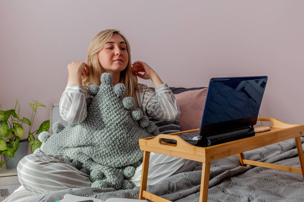 Young business woman meditates while sitting on the bed, after work Internet using a computer. Girl listens calm music near the laptop. Home comfort zone and wellness concept. - Φωτογραφία, εικόνα
