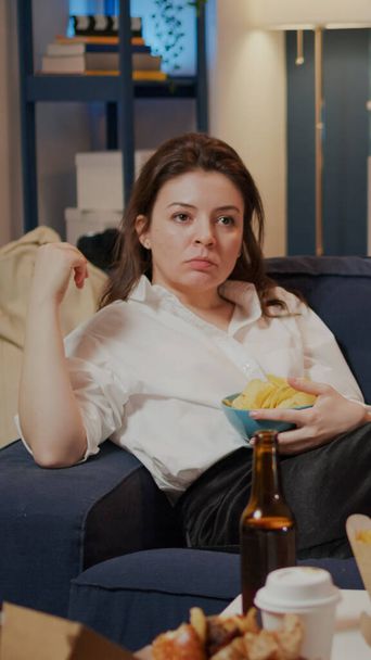Caucasian adult relaxing on couch with chips as snack - Photo, Image