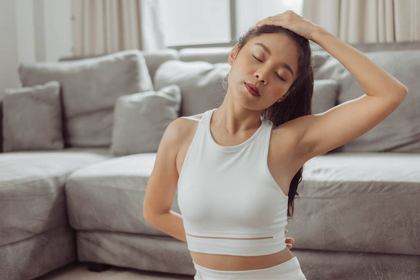 Woman stretching arms after exercise at home. Young asian healthy woman in sportwear workout at home. Home exercise. - Foto, Imagem
