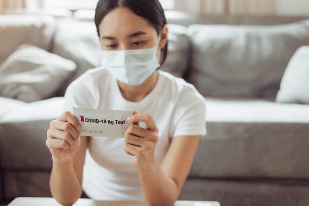 mulher estudando as instruções para um auto-teste para COVID-19 com kit de antígeno. mulher asiática usando coronavírus covid-19 kit de teste caseiro de antígeno rápido, teste de swab nasal Coronavirus para infecção. - Foto, Imagem