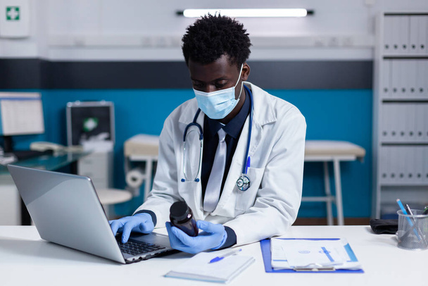 Persona negra con profesión médica usando laptop - Foto, imagen