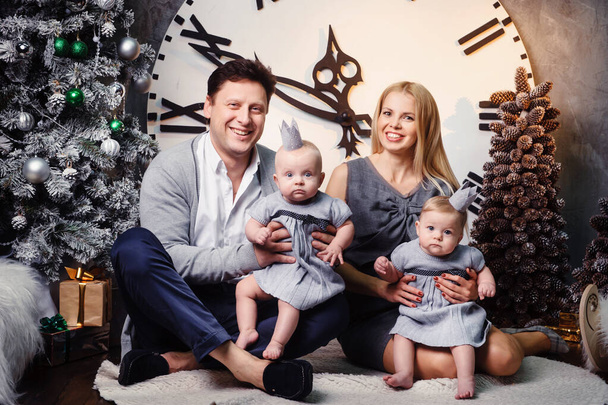 Una grande famiglia felice con bambini gemelli nell'interno della casa di Capodanno sullo sfondo di un grande orologio. - Foto, immagini