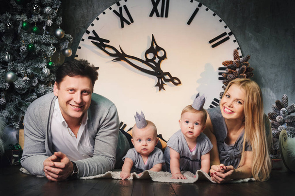 A happy big family with twin children in the New Year's interior of the house against the background of a large clock. - Fotoğraf, Görsel