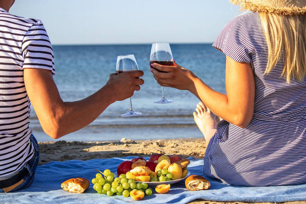 Beautiful smiling woman with a glass of wine on the beach. Fruit red wine. Selective focus. - Foto, afbeelding