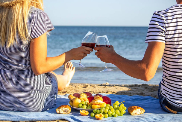 Bela mulher sorridente com um copo de vinho na praia. Vinho tinto de fruta. Foco seletivo. - Foto, Imagem