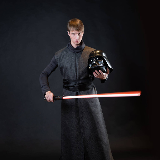 A villain with a red lightsaber, a young man in a long robe does fighting poses, - Photo, image