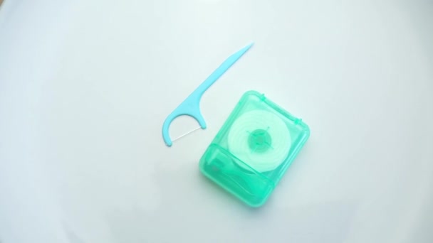 Rotierender Zahnseidenstock und Box mit Zahnseidenrolle auf weißem Hintergrund - Filmmaterial, Video
