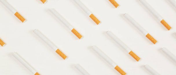Beyaz arka planda ticari olarak yapılmış birkaç sigara yığını görüntüsü. sigara içilmeyen kampanya konsepti, tütün desenli üst görünüm. - Fotoğraf, Görsel