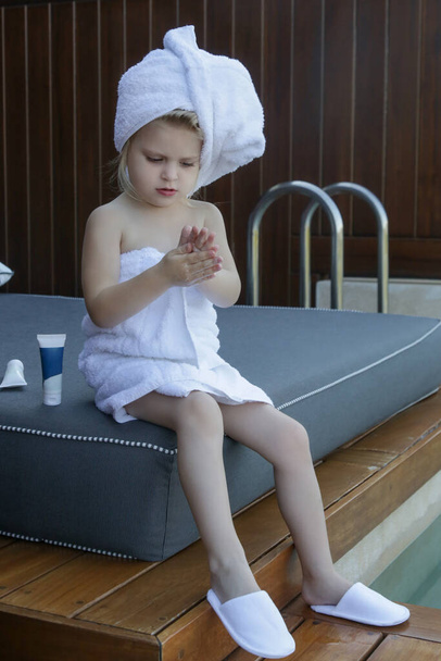Producto de cuidado de la piel para niños. Niña envuelta en toallas usando productos para el cuidado de la piel. - Foto, Imagen