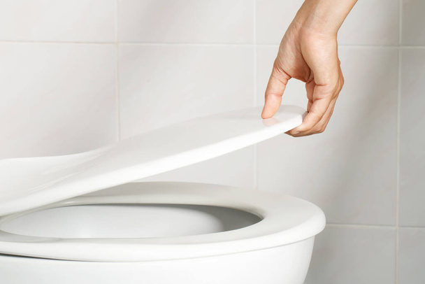 férfi keze kinyitja a WC fedelet - Fotó, kép