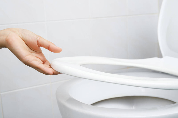 Main de femme ouvrant le couvercle des toilettes - Photo, image