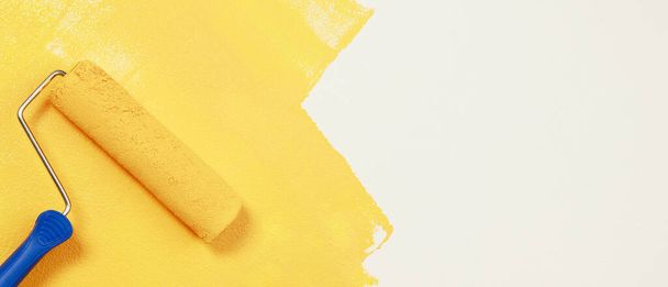 Pintura del pincel del rodillo, pintura del trabajador en la pared superficial Pintura apartamento, renovando con pintura de color amarillo. - Foto, Imagen