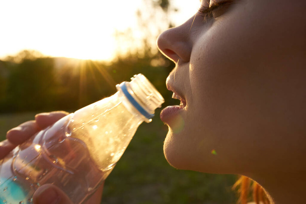 mujer alegre bebiendo agua de una botella transparente - Foto, imagen