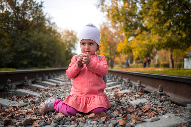 linda niña jugando con piedras en el terraplén del ferrocarril. juegos peligrosos - Foto, imagen