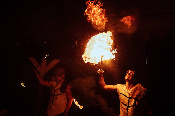 un artista de fuegos artificiales en una máscara de una criatura mítica realiza con fuego. festival de cultura callejera. espectáculo de fuego místico colorido por la noche - Foto, Imagen