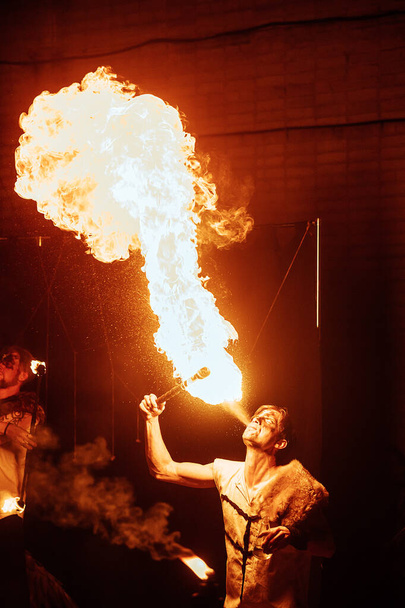 un artista di spettacolo pirotecnico in una maschera di una creatura mitica si esibisce con il fuoco. festival della cultura di strada. colorato spettacolo di fuoco mistico di notte - Foto, immagini