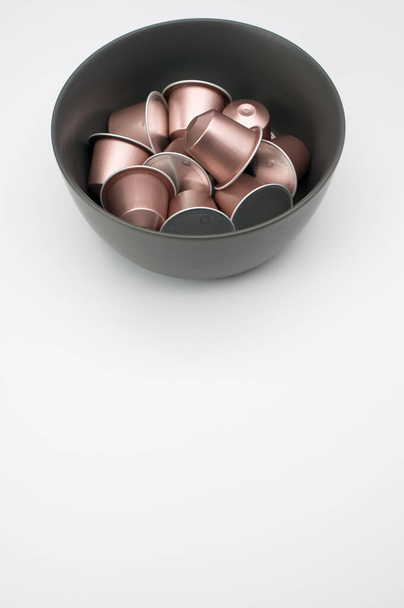 A vertical shot of espresso capsules in a bowl on a white background - Foto, Imagem