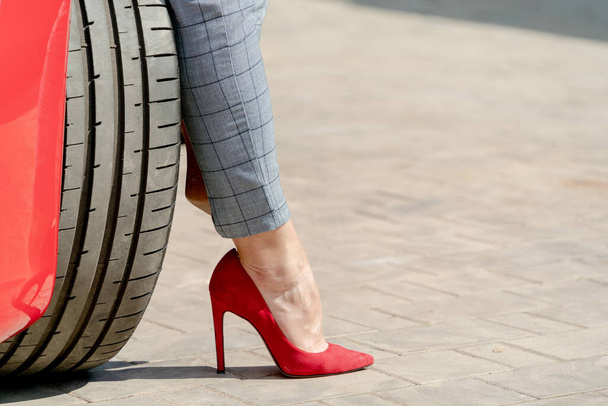 A selective of a female's foot in red heel near the car on a summer sunny day - Photo, Image