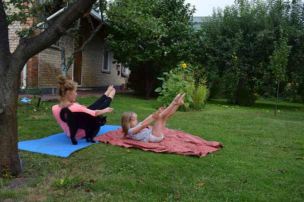 Anya és lánya együtt jógáznak a kertben.. - Fotó, kép