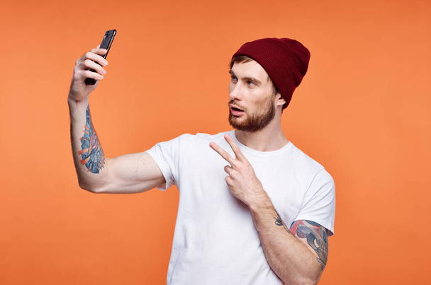 hombre con un teléfono en sus manos sombrero de moda posando estudio - Foto, Imagen