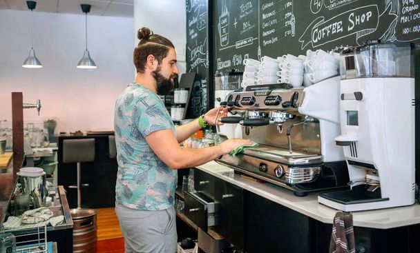 Fiatal pincér tisztítja a kávéfőzőt - Fotó, kép