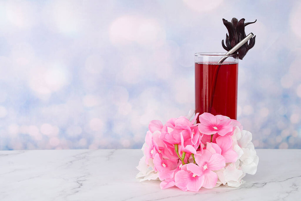 Un bicchiere di bevande Roselle con paglia di metallo e fiori - Foto, immagini