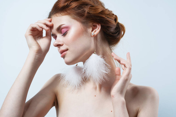 vrouw met blote schouders en heldere make-up sieraden pluizig oorbellen - Foto, afbeelding