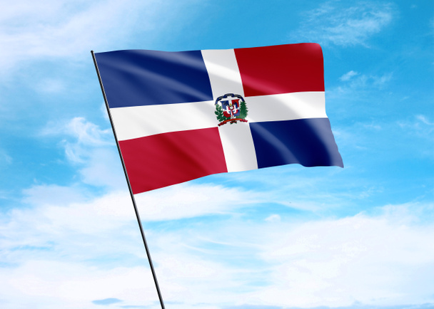 Flaga Dominikany powiewa wysoko na niebie. 27 lutego Dominikana Dzień Niepodległości Światowa kolekcja flag narodowych - Zdjęcie, obraz