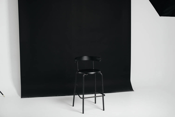 A stylish black chair stands on a black background in the studio room. The concept of a vacancy or an interview. Cinema, director's chair. - 写真・画像