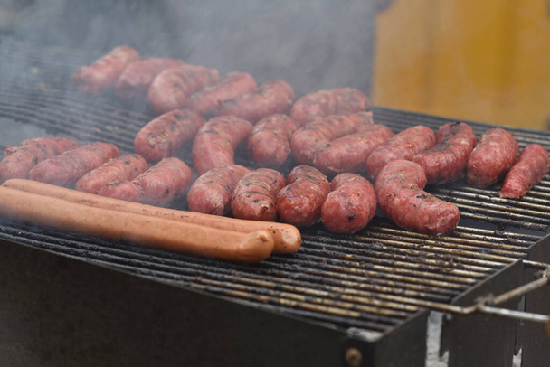 A number of sausages grilling outdoors in the backyard - Foto, imagen