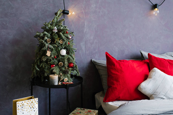 Pequena árvore de Natal na mesa de cabeceira e presentes perto da cama no quarto elegante - Foto, Imagem