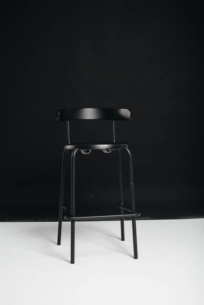 A stylish black chair stands on a black background in the studio room. The concept of a vacancy or an interview. Cinema, director's chair. - Foto, imagen
