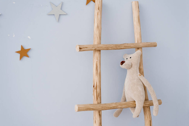 柔らかいおもちゃのクマは子供部屋の装飾で木製の階段に座っています - 写真・画像