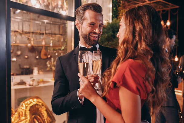 Beautiful young couple in formalwear toasting with champagne while spending time on luxury party - Фото, изображение
