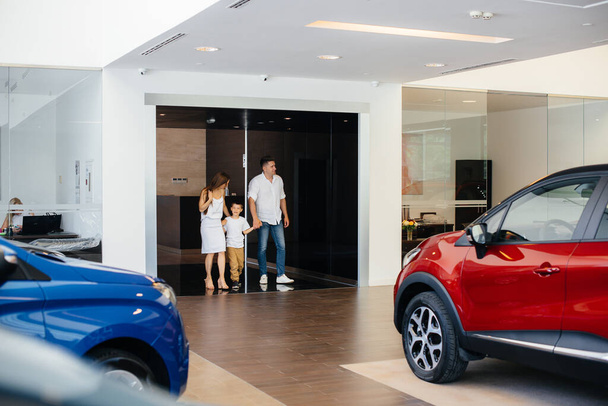 A happy young family chooses and buys a new car at a car dealership. Buying a new car - Foto, Imagem