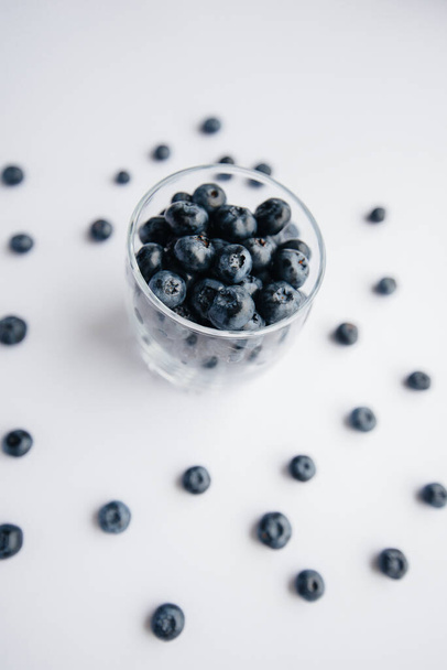 Beautiful ripe blueberries in a transparent glass glass on a white background. Healthy food, and vitamins. - Fotografie, Obrázek