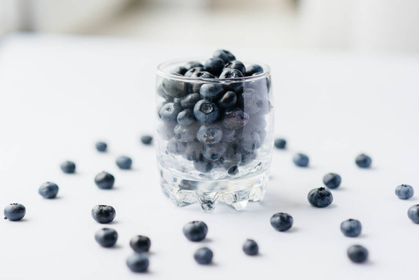 Beautiful ripe blueberries in a transparent glass glass on a white background. Healthy food, and vitamins. - Zdjęcie, obraz