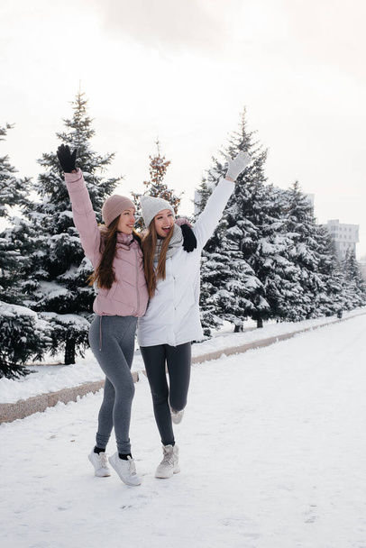 Two young athletic girls walking and playing sports on a sunny winter day. A healthy way of life. - Foto, Imagen