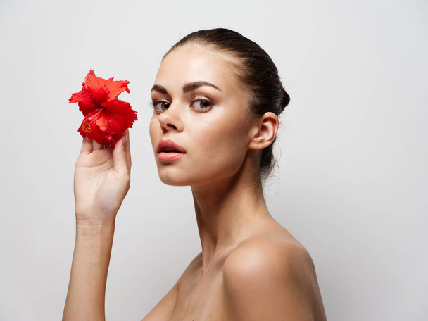 young woman with a flower in front of her eyes on a light background  - Photo, image