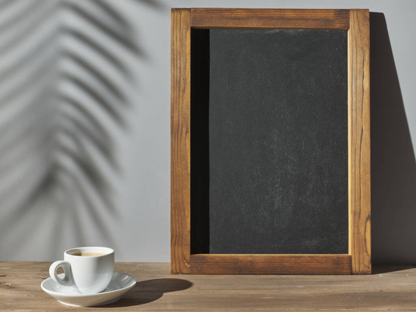 Espresso cup and chalk board near gray wall - Foto, afbeelding